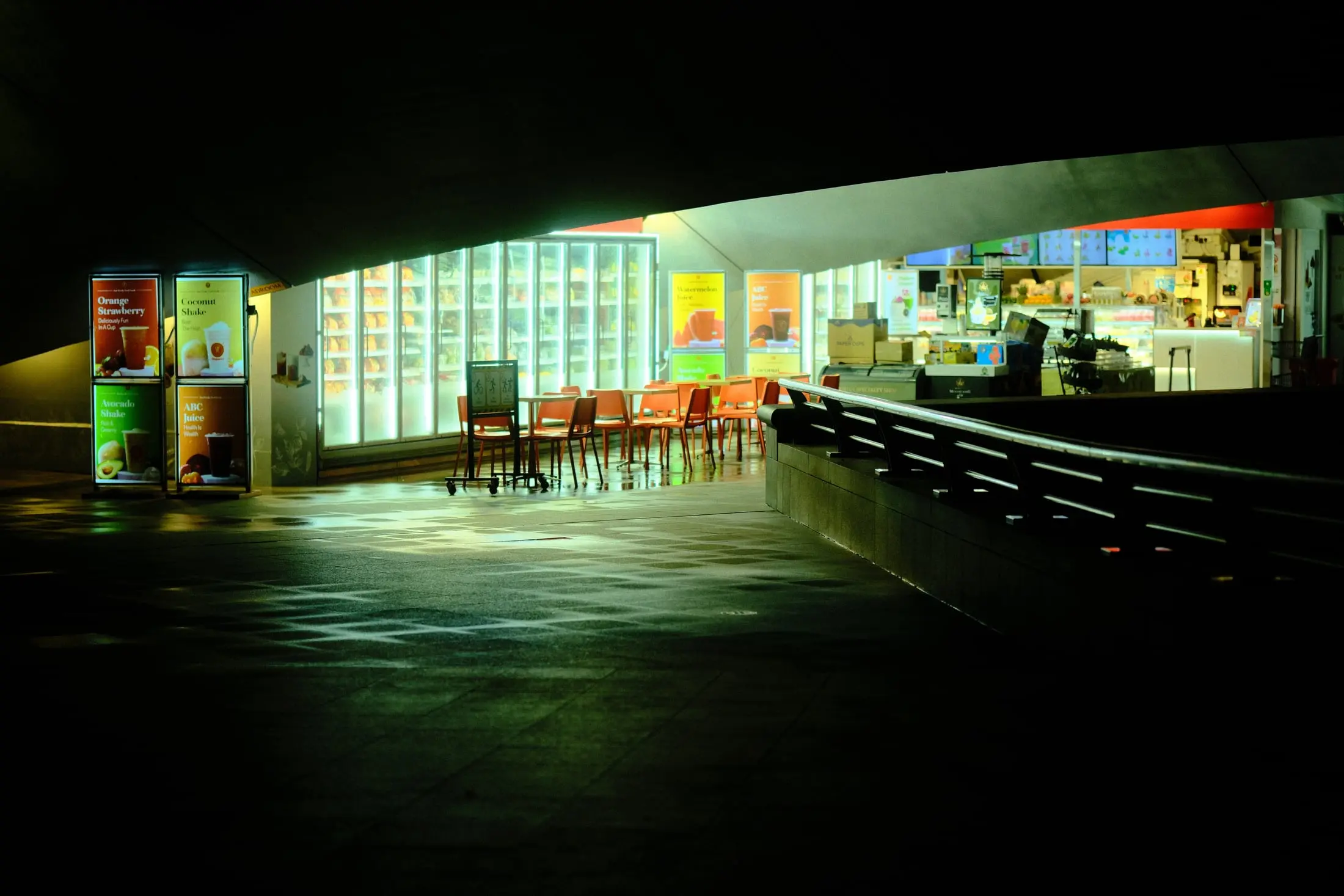 A brightly lit convenience store framed by the dark underside of Esplanade Bridge in Singapore