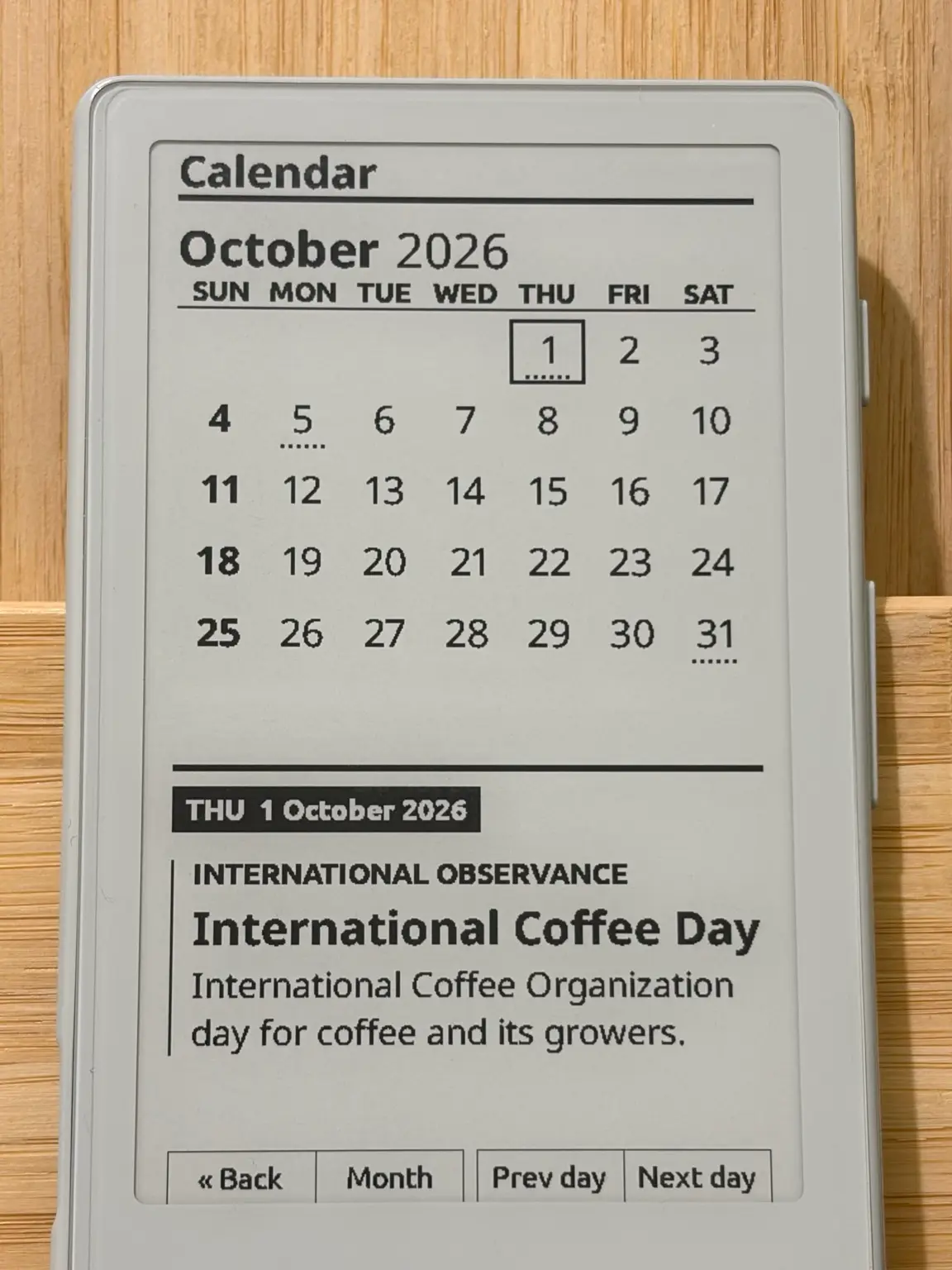Calendar on an XTEINK X4 showing October 2026 with International Coffee Day selected and button labels for Back, Month, Prev day and Next day.
